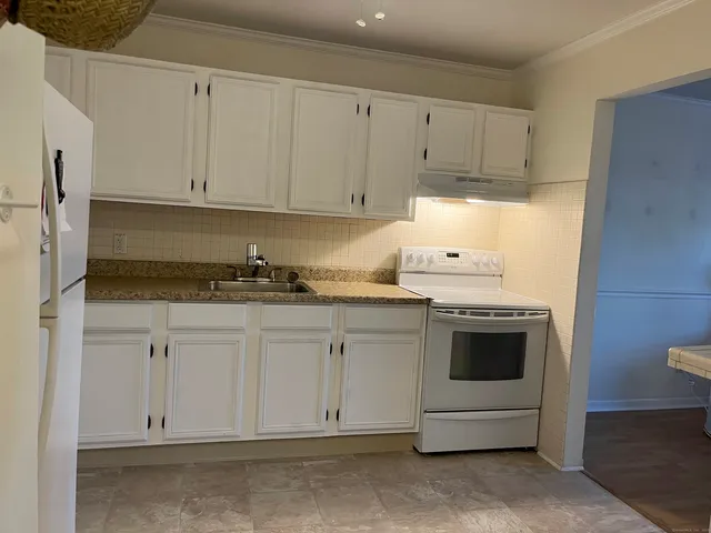 a kitchen with granite countertop white cabinets and white appliances