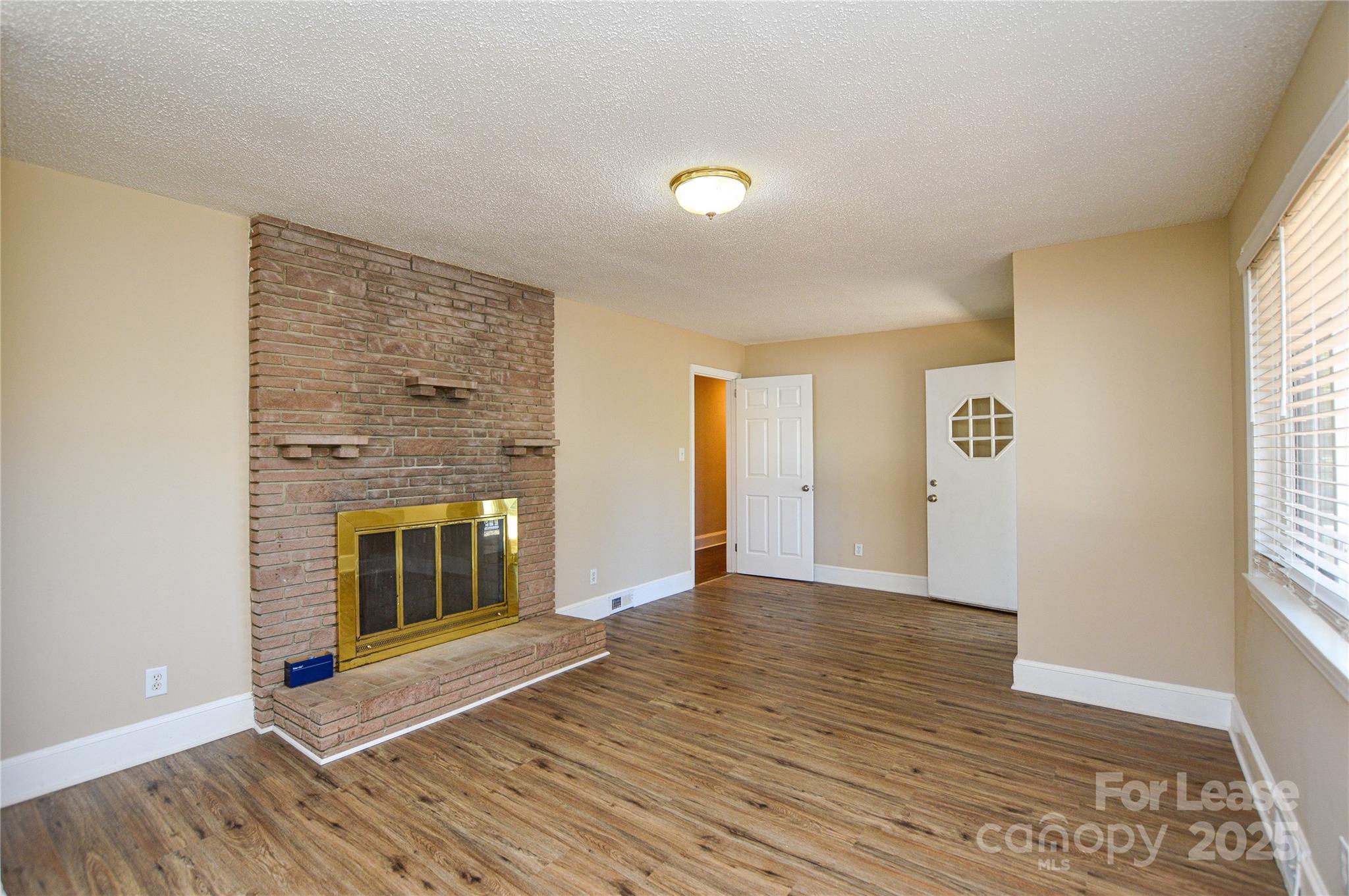2511 Woodstar Road Matthews, NC 28105 - Photo 18 of 21 an empty room with wooden floor fireplace and windows