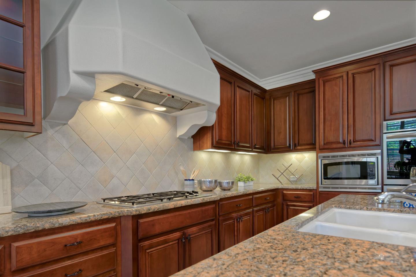 7160 Eagle Ridge Drive Gilroy, CA 95020 - Photo 16 of 80 a kitchen with granite countertop a stove top oven a sink dishwasher and cabinets with wooden floor