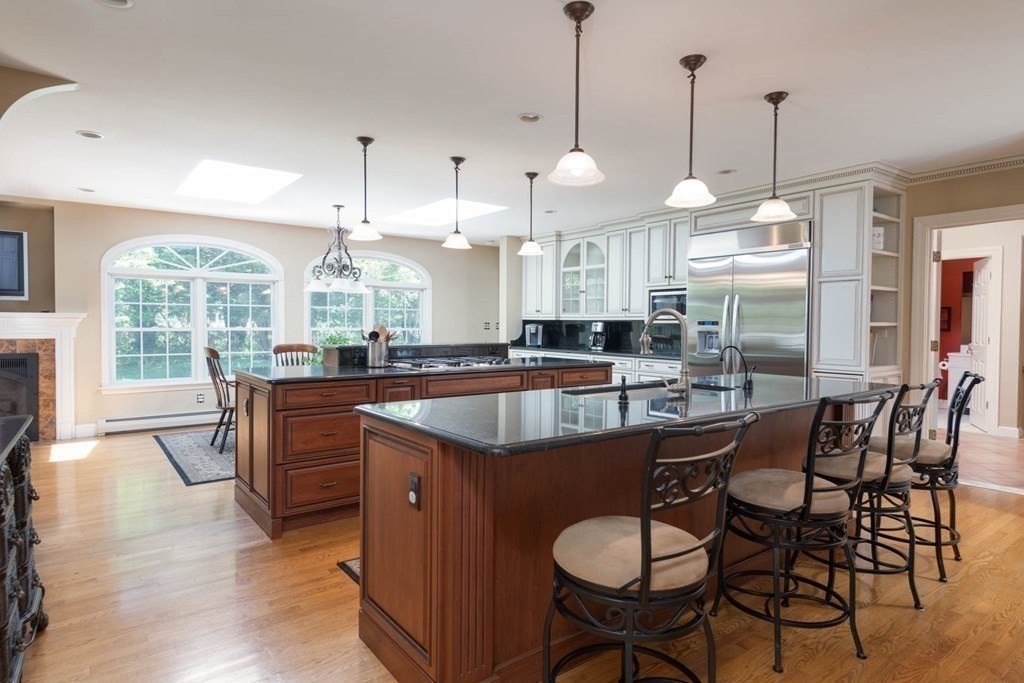 4 Elliston Road Weston, MA 02493 - Photo 13 of 36 a kitchen with stainless steel appliances granite countertop a stove a sink a microwave a dining table and chairs with wooden floor