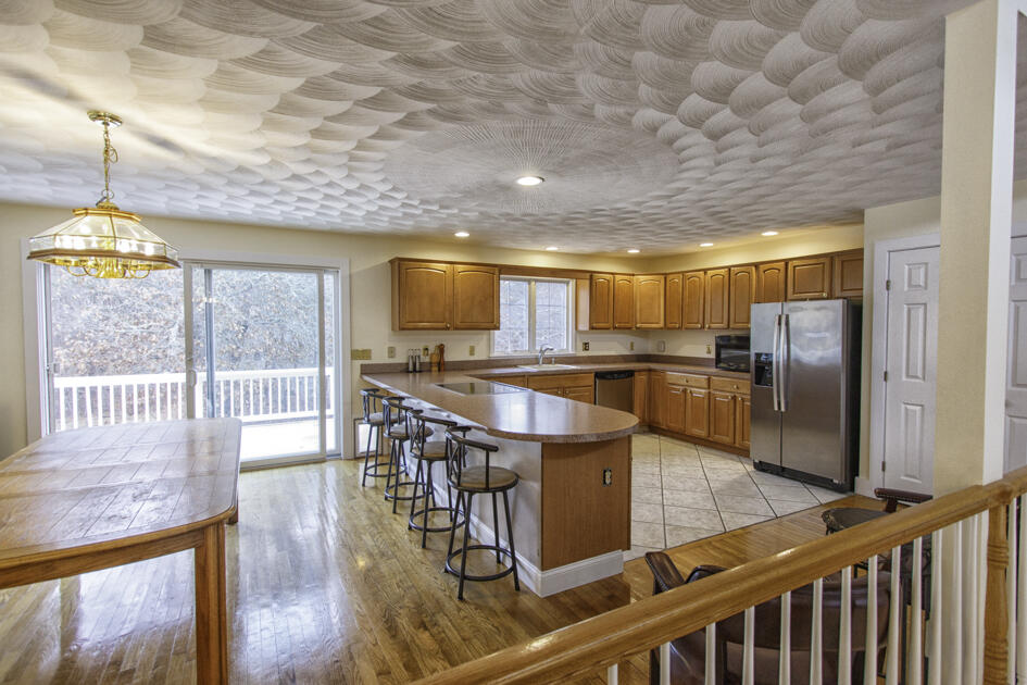 488 Upper County Road Dennis Port, MA 02639 - Photo 15 of 35 a kitchen with stainless steel appliances kitchen island granite countertop a stove a refrigerator a dining table and chairs with wooden floor