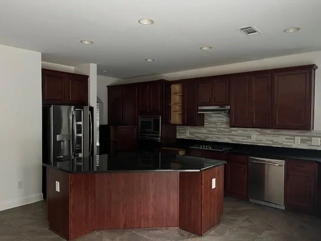 a kitchen with stainless steel appliances granite countertop a refrigerator and a stove top oven