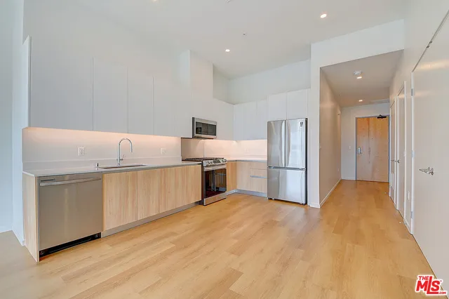 a kitchen with granite countertop a sink a counter top space stainless steel appliances and cabinets