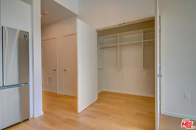 a view of an empty room with wooden floor and closet