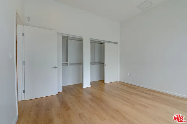 a view of an empty room with wooden floor and cabinets