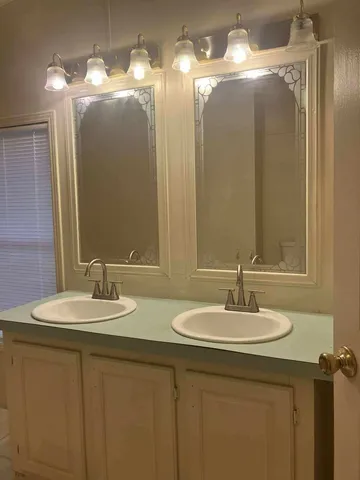 a bathroom with double vanity sinks and a mirror
