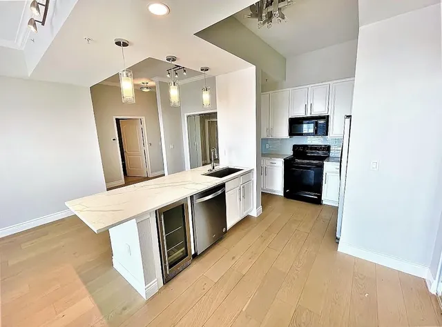 a view of kitchen with stainless steel appliances wooden floor and window