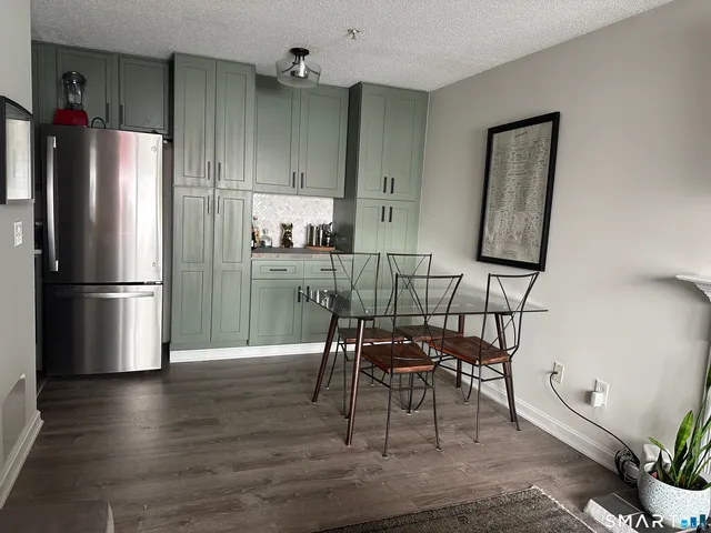 a kitchen with granite countertop a refrigerator cabinets wooden floor and a dining table