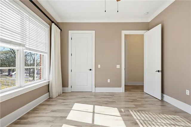 a view of an empty room with wooden floor and a window