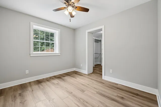 a view of an empty room with a window and wooden floor