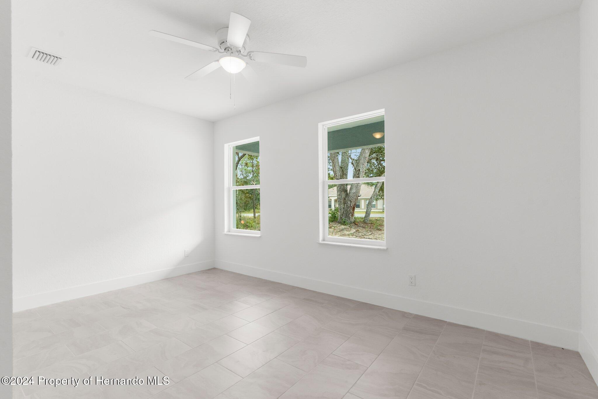 15214 Mt Sparrow Road Brooksville, FL 34614 - Photo 21 of 36 an empty room with windows and ceiling fan