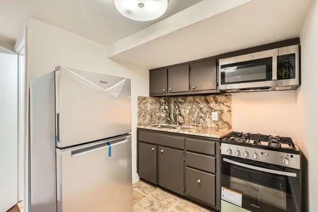 a kitchen with stainless steel appliances granite countertop a refrigerator and a stove top oven