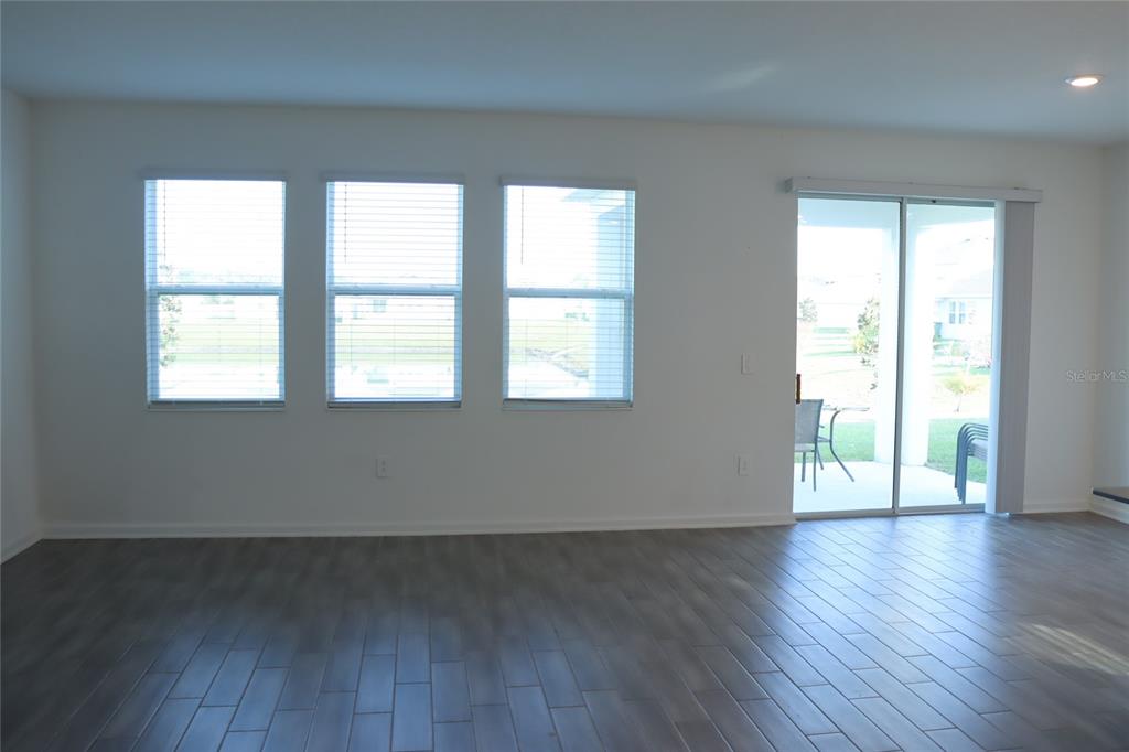 34558 Shellback Street Leesburg, FL 34788 - Photo 14 of 36 an empty room with wooden floor and windows