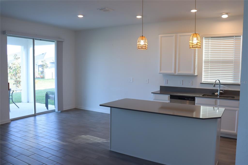 34558 Shellback Street Leesburg, FL 34788 - Photo 6 of 36 a kitchen with kitchen island granite countertop a stove a sink and a large window
