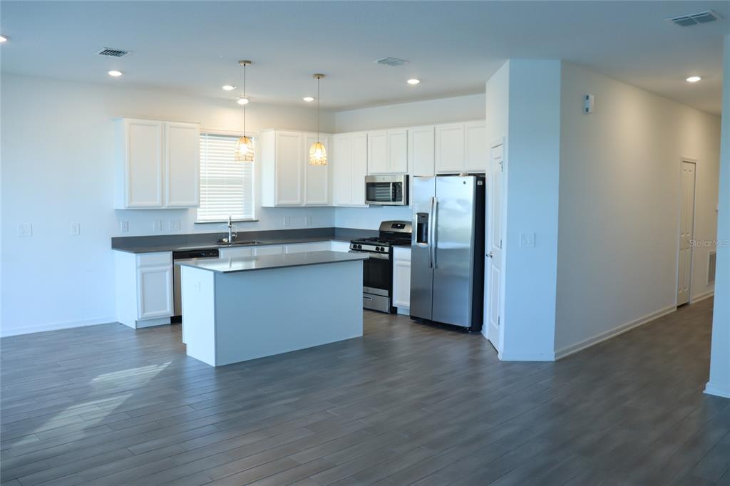 34558 Shellback Street Leesburg, FL 34788 - Photo 9 of 36 a kitchen with stainless steel appliances granite countertop a refrigerator a stove a sink and a microwave