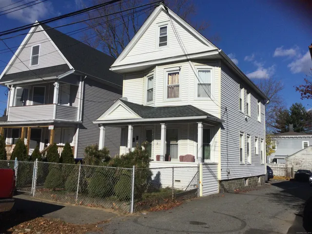 a view of a white house with large windows and table and chairs