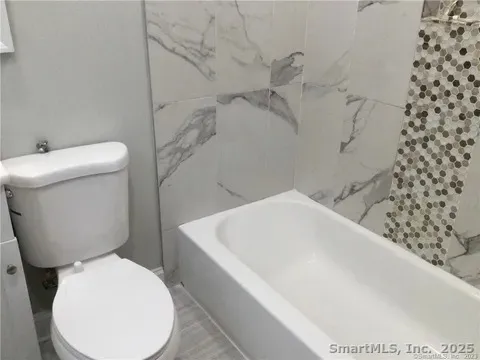 a white toilet sitting next to a bath tub