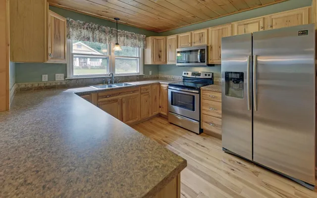 a kitchen with granite countertop a refrigerator and a stove top oven
