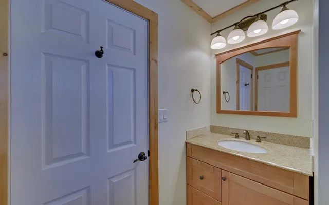 a bathroom with a granite countertop sink vanity and mirror