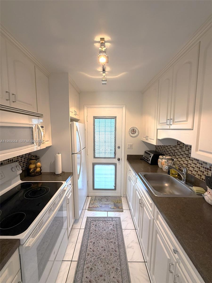 17000 Northeast 14th Avenue, Unit 206 Miami, FL 33162 - Photo 6 of 15 a kitchen with granite countertop a sink stove and cabinets