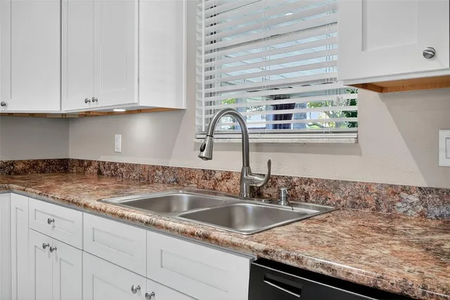 a kitchen with granite countertop a sink and white cabinets