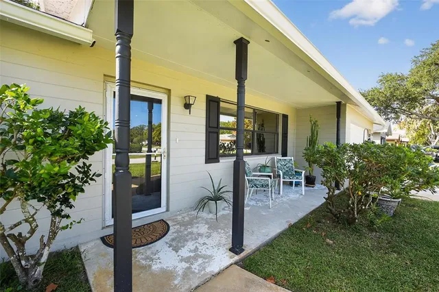 a view of a patio with table and chairs potted plants and floor to ceiling window