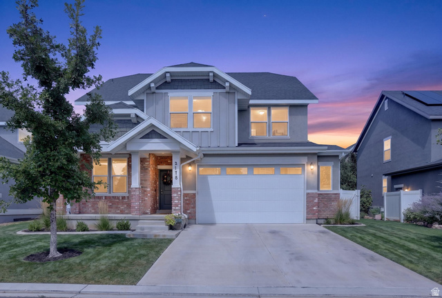 Two-story residence featuring brick and siding facade, covered front porch, attached garage, and a concrete driveway