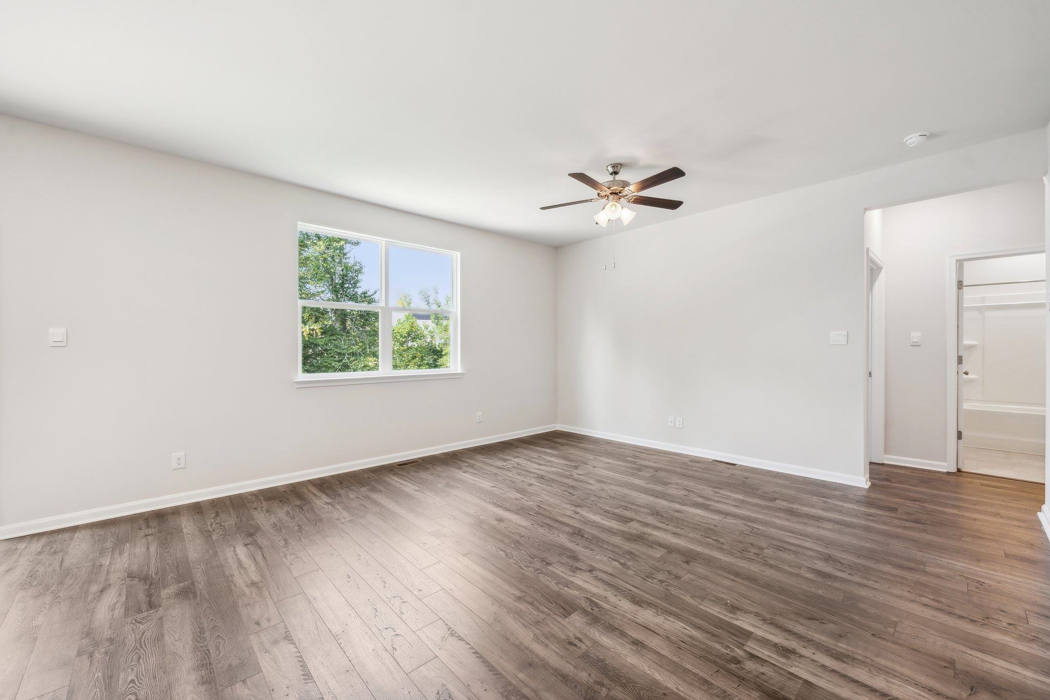 240 Waterfront Drive Raphine, VA 24472 - Photo 10 of 29 an empty room with wooden floor chandelier fan and windows