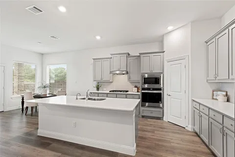 a large white kitchen with lots of counter top space a refrigerator a stove and a cabinets