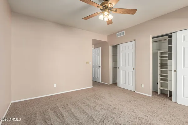 an empty room with closet and a chandelier fan