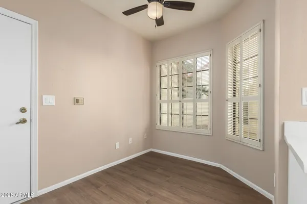 an empty room with chandelier fan and windows