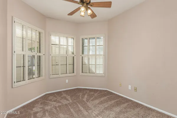 an empty room with chandelier fan and windows