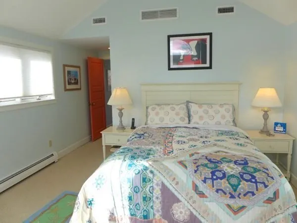 a bedroom with a bed and a lamp on dresser