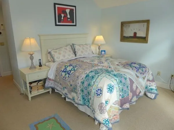 a bedroom with bed and a lamp on dresser