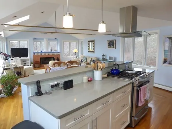 a kitchen with a stove a sink dishwasher and a dining table with wooden floor