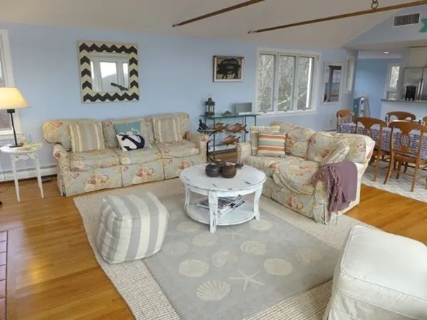 a living room with furniture and a dining table with wooden floor