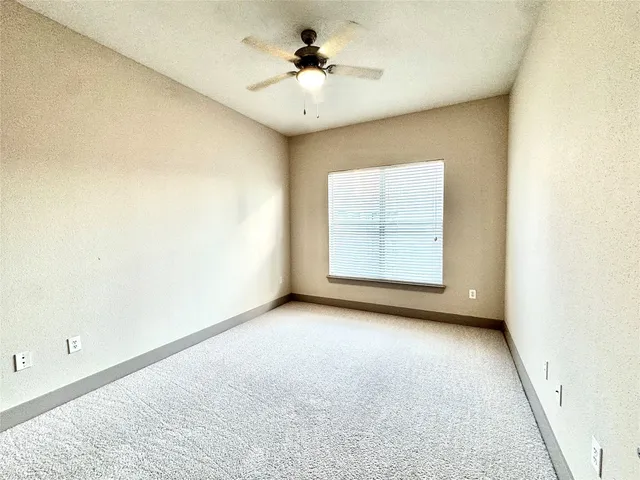 an empty room with windows and ceiling fan