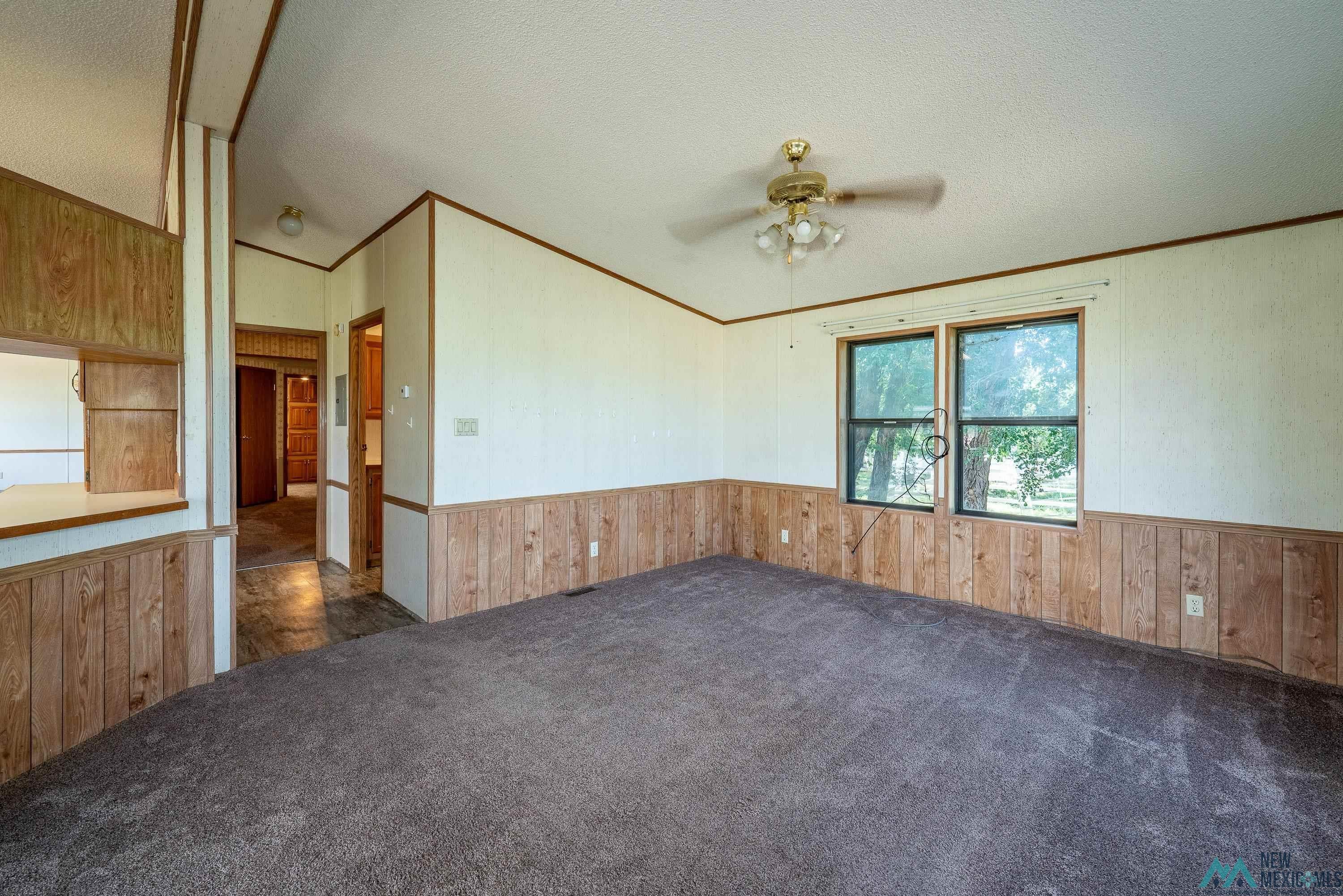 35234 Highway 87 Raton, NM 87740 - Photo 40 of 90 Unfurnished room with wooden walls, a wainscoted wall, crown molding, dark carpet, and a textured ceiling