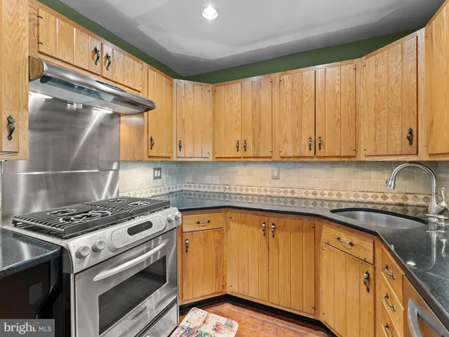 a kitchen with granite countertop a sink stove and cabinets