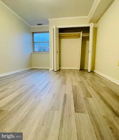 a view of an empty room with wooden floor and closet