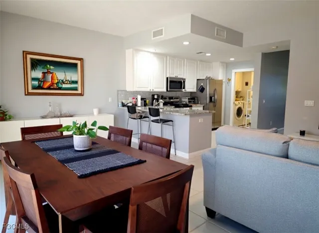 a living room with stainless steel appliances furniture a dining table and chairs