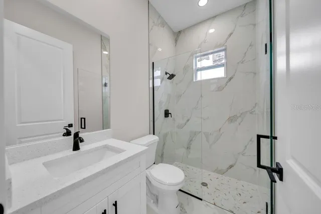 a bathroom with a sink toilet a mirror and shower