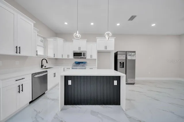a kitchen with kitchen island a sink stainless steel appliances and cabinets
