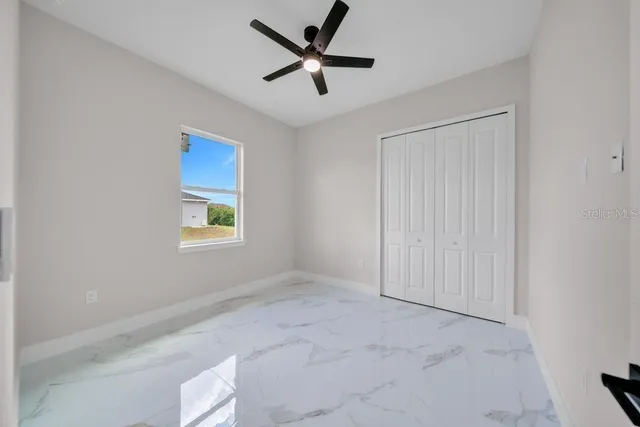 an empty room with windows and a ceiling fan