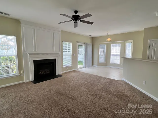 an empty room with a fireplace and a chandelier fan