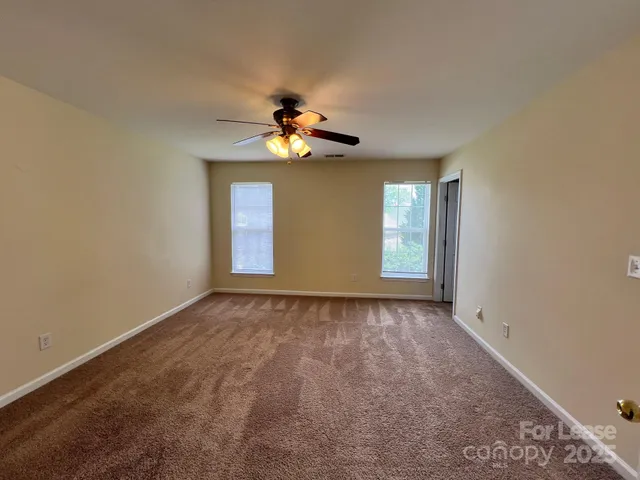 a view of an empty room with a chandelier fan