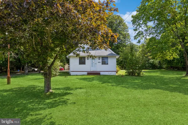a front view of house with yard and trees in the background