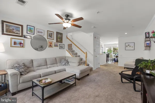 a living room with furniture a chandelier fan and a window