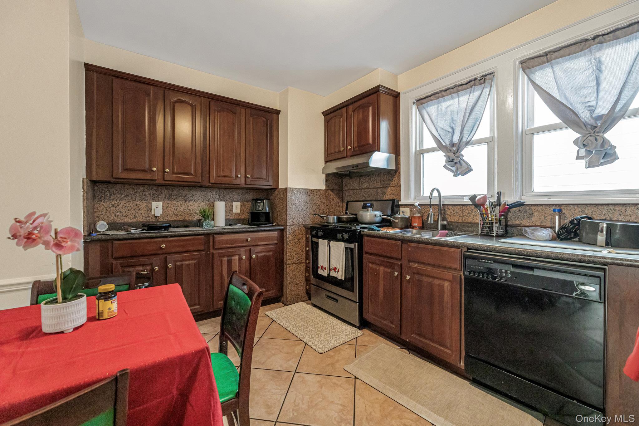 168 Stephenson Boulevard New Rochelle, NY 10801 - Photo 19 of 21 Kitchen with dark brown cabinets, stainless steel range with gas stovetop, dishwasher, dark countertops, and light tile patterned floors