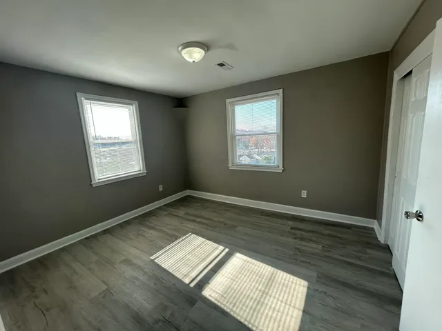 a view of an empty room and window and wooden floor